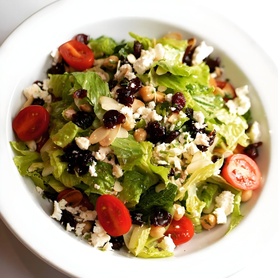 A fresh Italian salad with lettuce, cherry tomatoes, feta, chickpeas, dried cranberries, and almonds.