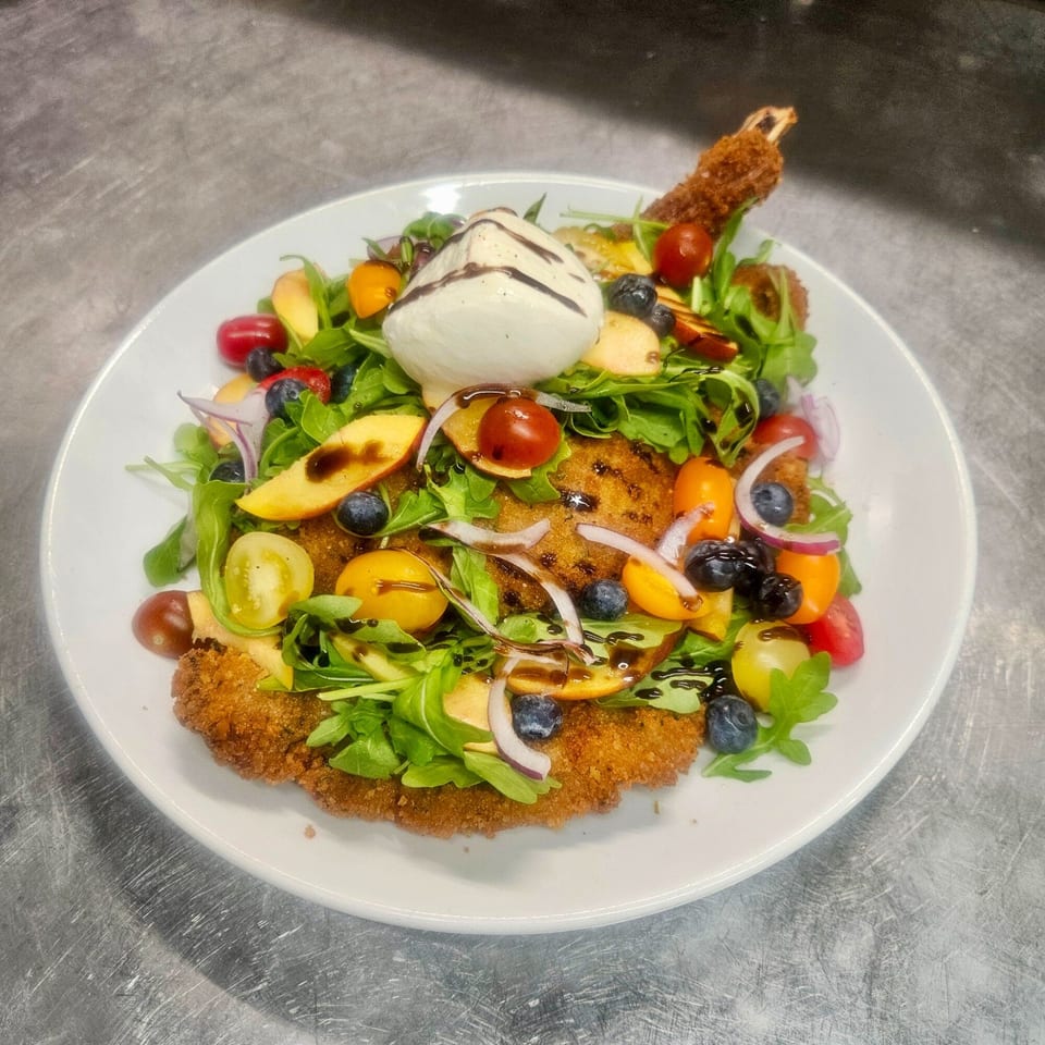 Rosario's Trattoria & Pizzeria's breaded chicken cutlet topped with arugula, fruit, and burrata.