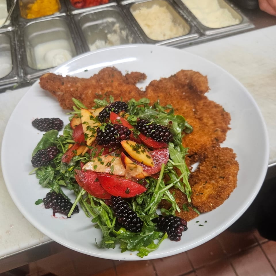 Crispy breaded chicken cutlets with a fresh arugula salad, blackberries, and sliced fruit.