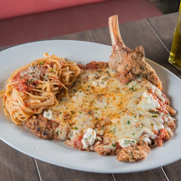 Rosario's Trattoria & Pizzeria's veal parmesan with linguine and tomato sauce on a white plate.