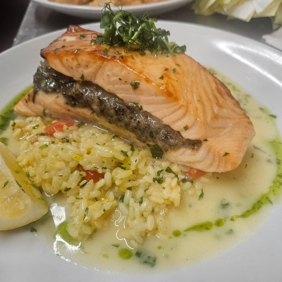 Rosario's Trattoria & Pizzeria's salmon dish with risotto, lemon, and a creamy sauce.