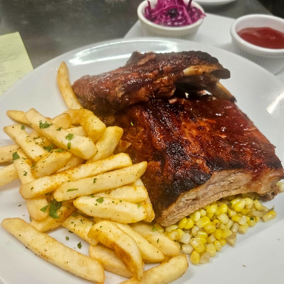 Rosario's Trattoria & Pizzeria's BBQ ribs with fries, corn, and sides of coleslaw and ketchup.
